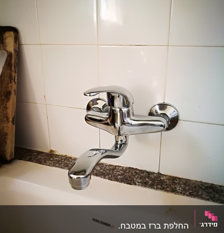 ברז כרום מותקן על קיר אריחים לבנים